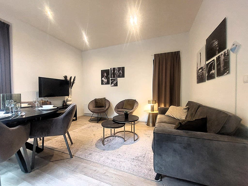 Moderne woonkamer met zithoek, eettafel, tv en decoratieve foto's aan de muur.