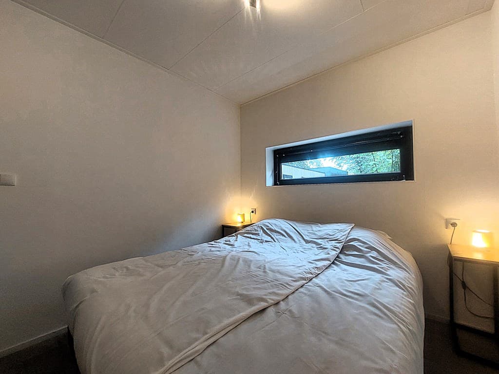 Slaapkamer met tweepersoonsbed, een raam met uitzicht naar buiten en nachtkastjes met lampjes