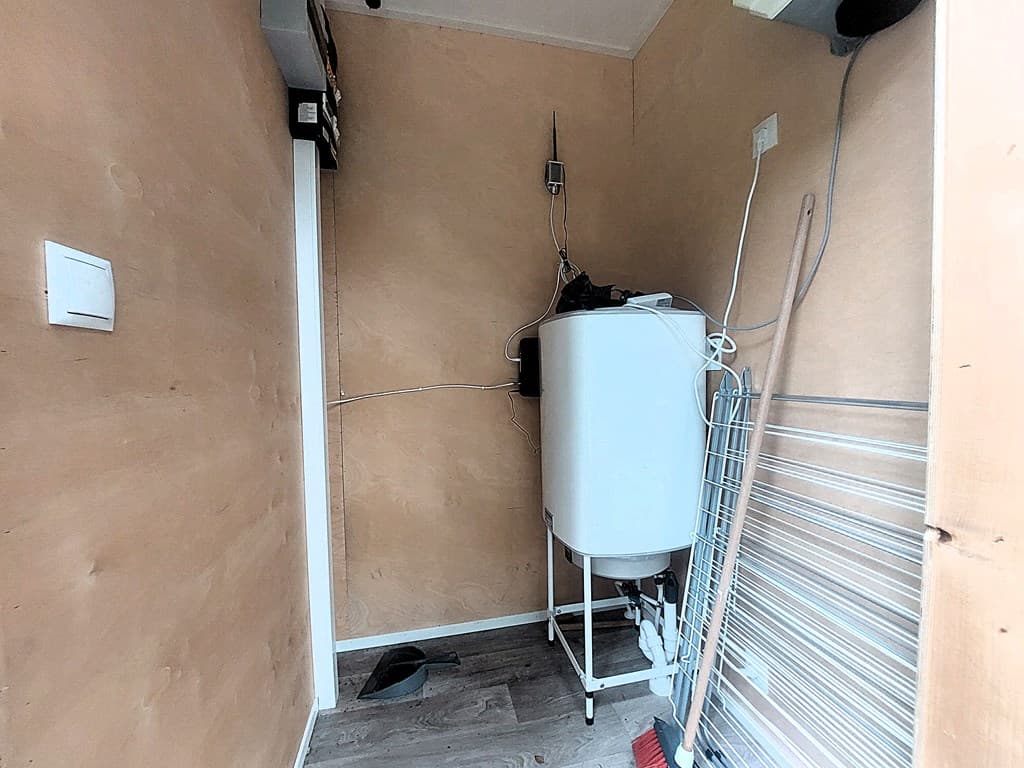 In een kleine ruimte staan een boiler en een verwarmingsradiator tegen de wand.